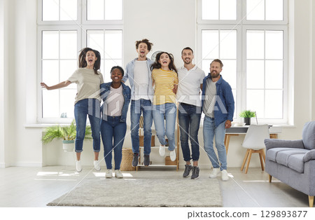 Happy exciting mixed race friends jumping posing for photo and smiling looking at camera. Happy exciting mixed race friends jumping posing for photo and smiling looking at camera. 129893877
