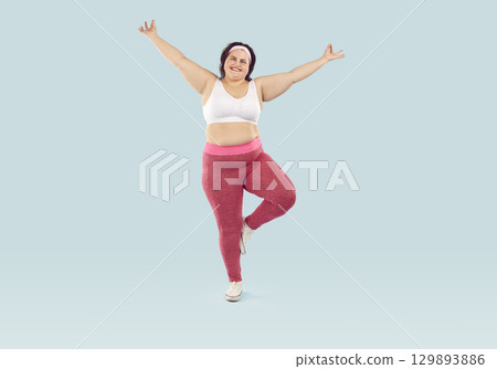Happy overweight woman doing exercise and standing on one leg during fitness workout Happy overweight woman doing exercise and standing on one leg during fitness workout 129893886