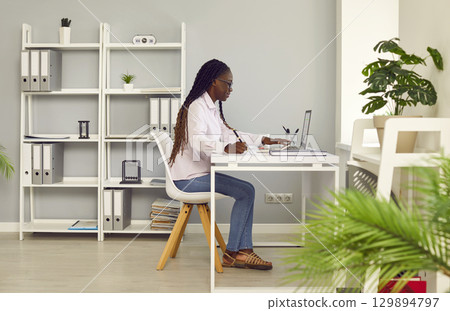 Young business african american woman working on a laptop at modern office. 129894797