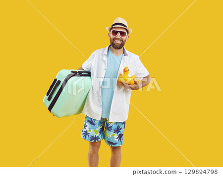 Happy male tourist with suitcase and toy duck is going on summer vacation to sea 129894798