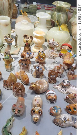 Unique ceramic onyx stone figurines displayed at a craft fair highlighting intricate designs and vibrant colors 129894837