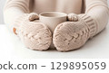 Blank soft mittens worn, holding mug, isolated 129895059