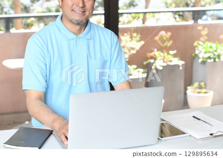 Smiling Asian man doing office work on a PC Smiling Asian man doing office work on a PC 129895634