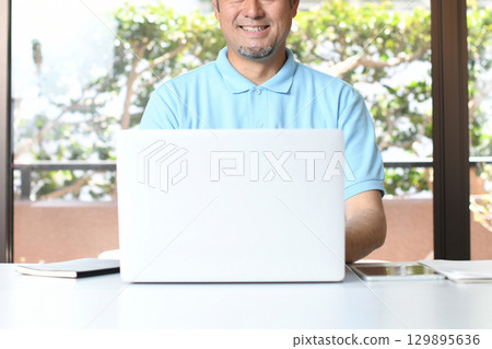 一名微笑的亞洲男子在電腦上做辦公室工作 一名微笑的亞洲男子在電腦上做辦公室工作 129895636