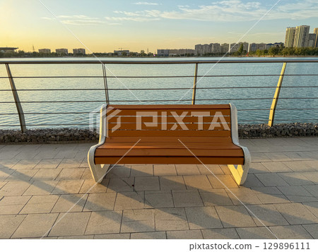 Modern bench on waterfront promenade at sunset Modern bench on waterfront promenade at sunset 129896111