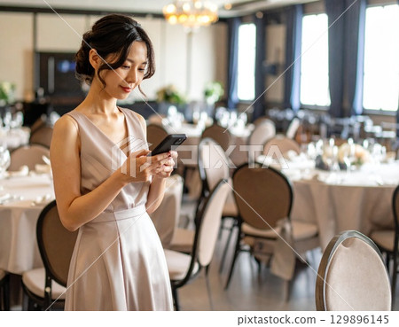 A woman in a dress holding a smartphone 129896145