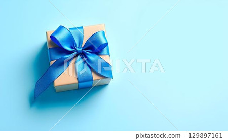 Gift box with a blue ribbon on a blue background, celebrating Father's Day with a festive touch Gift box with a blue ribbon on a blue background, celebrating Father's Day with a festive touch 129897161