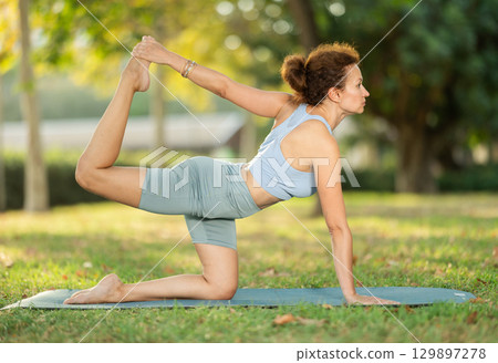Woman doing yoga with wooden blocks on mat early morning outdoors Woman doing yoga with wooden blocks on mat early morning outdoors 129897278