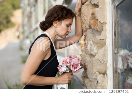 Woman brought flowers to the cemetery and cries over the death of beloved relative 129897401