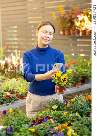 Woman looking for name of violet on phone 129897421