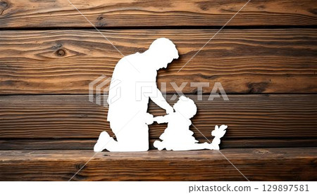 A charming paper cutout depicting a father and daughter holding hands, placed on a rustic wooden background for Father's Day 129897581