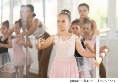 Girls in ballet class perform forth position with correction of female mentor Girls in ballet class perform forth position with correction of female mentor 129897725