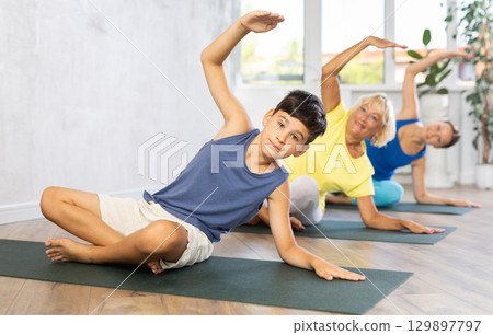 Family is smiling and happily practicing yoga in sports center Family is smiling and happily practicing yoga in sports center 129897797