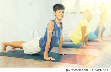 Preteen boy practicing upward facing dog pose of yoga in fitness room Preteen boy practicing upward facing dog pose of yoga in fitness room 129897841
