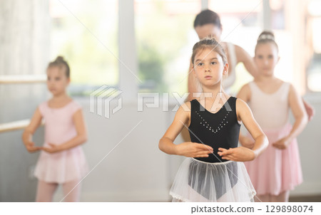 Girls in ballet class perform first position with correction of female mentor Girls in ballet class perform first position with correction of female mentor 129898074