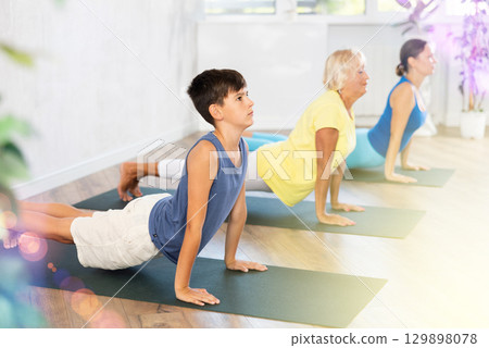 Mother, grandmother and teen son do exercise upward facing dog pose, Urdhva Mukha Svanasana pose Mother, grandmother and teen son do exercise upward facing dog pose, Urdhva Mukha Svanasana pose 129898078