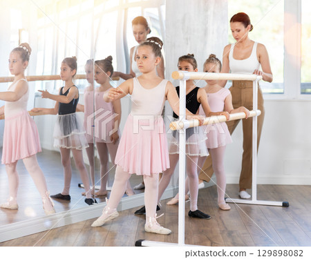 Girls in ballet class perform Batman with correction of female mentor Girls in ballet class perform Batman with correction of female mentor 129898082