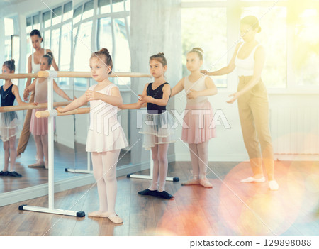 Girls in ballet class perform first position with correction of female mentor Girls in ballet class perform first position with correction of female mentor 129898088