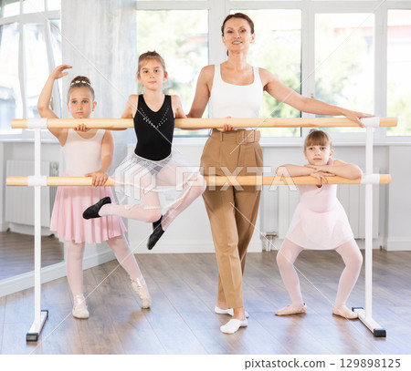 Choreography teacher posing with little girl students in ballet studio Choreography teacher posing with little girl students in ballet studio 129898125