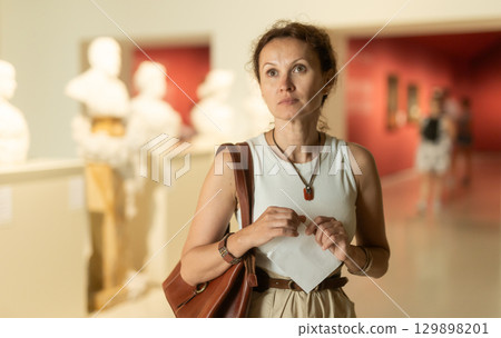 Positive woman looking at ancient bas-reliefs in old museum Positive woman looking at ancient bas-reliefs in old museum 129898201