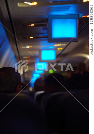 Group of people are sitting in an airplane with a blue screen in the middle of 129898562