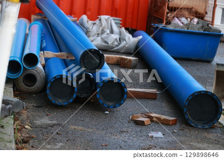 Pile of blue pipes and a blue plastic bucket 129898646