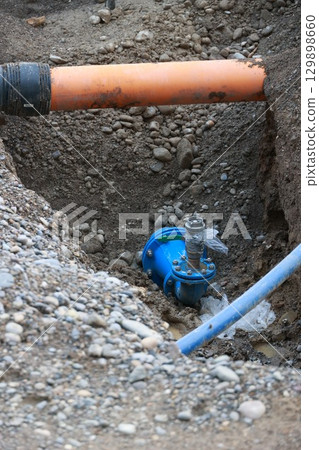 Blue pipe is in the ground next to a yellow pipe Blue pipe is in the ground next to a yellow pipe 129898660