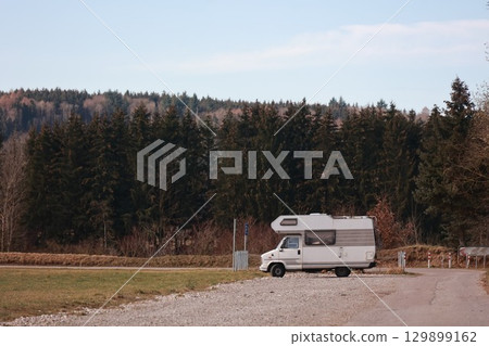 White camper van is parked in a field next to a road White camper van is parked in a field next to a road 129899162