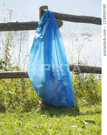 Blue plastic bag is hanging from a wooden fence Blue plastic bag is hanging from a wooden fence 129899398
