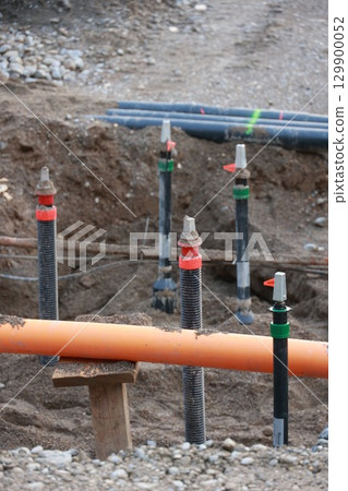 Bunch of pipes are in the dirt with orange cables Bunch of pipes are in the dirt with orange cables 129900052