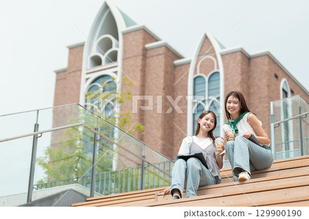 一位女大學生坐在長椅上喝咖啡 129900190