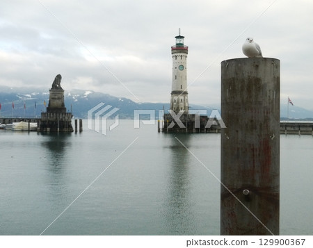 Lighthouse is in the distance with a bird perched on a post Lighthouse is in the distance with a bird perched on a post 129900367
