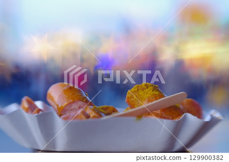 Plate of hot dogs with mustard and a wooden stick 129900382