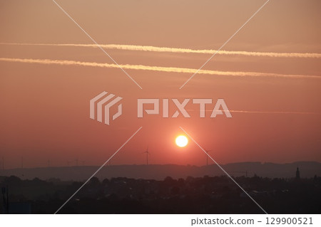 The sun is setting over a city with a beautiful orange sky 129900521