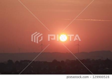 Sunset with a large sun and three wind turbines in the background Sunset with a large sun and three wind turbines in the background 129900528