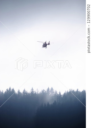 Helicopter is flying over a forest 129900702