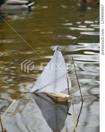 Small boat made of paper is floating in a pond Small boat made of paper is floating in a pond 129900807
