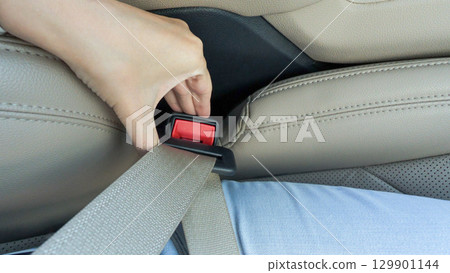 Hand reaching for car seatbelt buckle in a modern vehicle, showcasing safety features and emphasizing the importance of car safety practices 129901144