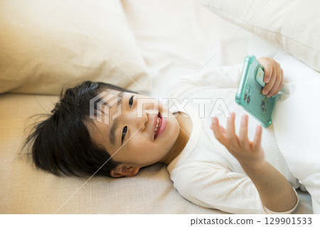 一個孩子躺著看智慧型手機 129901533