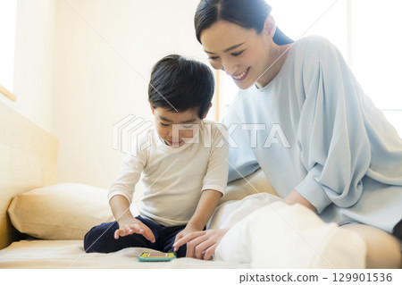 一個孩子躺著看智慧型手機 129901536