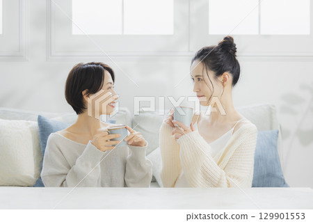 Woman drinking hot coffee in her room 129901553