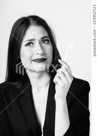 Woman holding white toothbrush in front of face 129902523