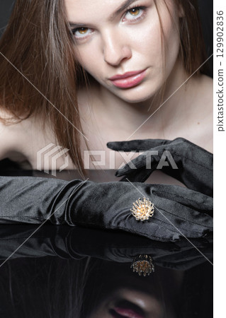 Close-up studio portrait of beautiful woman with fancy golden ring and black gloves 129902836