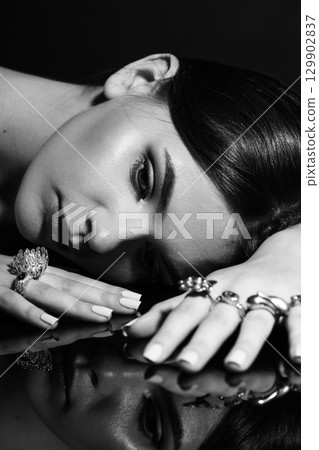 Studio portrait of beautiful and sexy woman with fancy make-up and various rings on her fingers 129902837