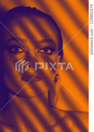 Blinds casts shadow on beautiful model with smokey make-up face studio portrait 129902874