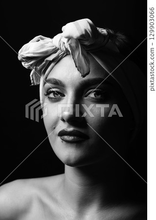 Portrait of beautiful woman with white scarf on her head looking at camera 129903066