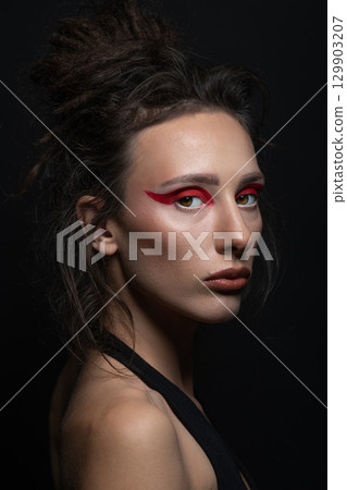 Studio portrait of beautiful woman with red eye shadows and dreadlocks Studio portrait of beautiful woman with red eye shadows and dreadlocks 129903207