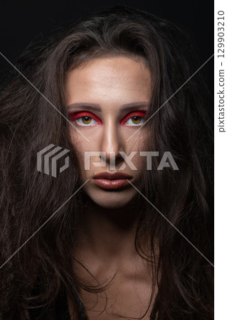 Studio portrait of beautiful woman with red eye shadows and dreadlocks 129903210