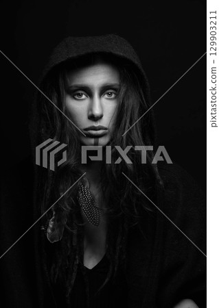 Model with make-up, dreadlocks, feather attached to her hair hiding under hood studio portrait Model with make-up, dreadlocks, feather attached to her hair hiding under hood studio portrait 129903211