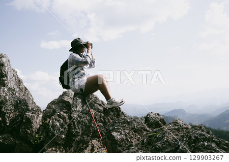 Woman hiker on top of mountain. Hiker with arms up on top of mountain successful young woman enjoying triumph. traveler exploring world. Hikers with backpacks relaxing. Sport and success concept. Woman hiker on top of mountain. Hiker with arms up on top of mountain successful young woman enjoying triumph. traveler exploring world. Hikers with backpacks relaxing. Sport and success concept. 129903267